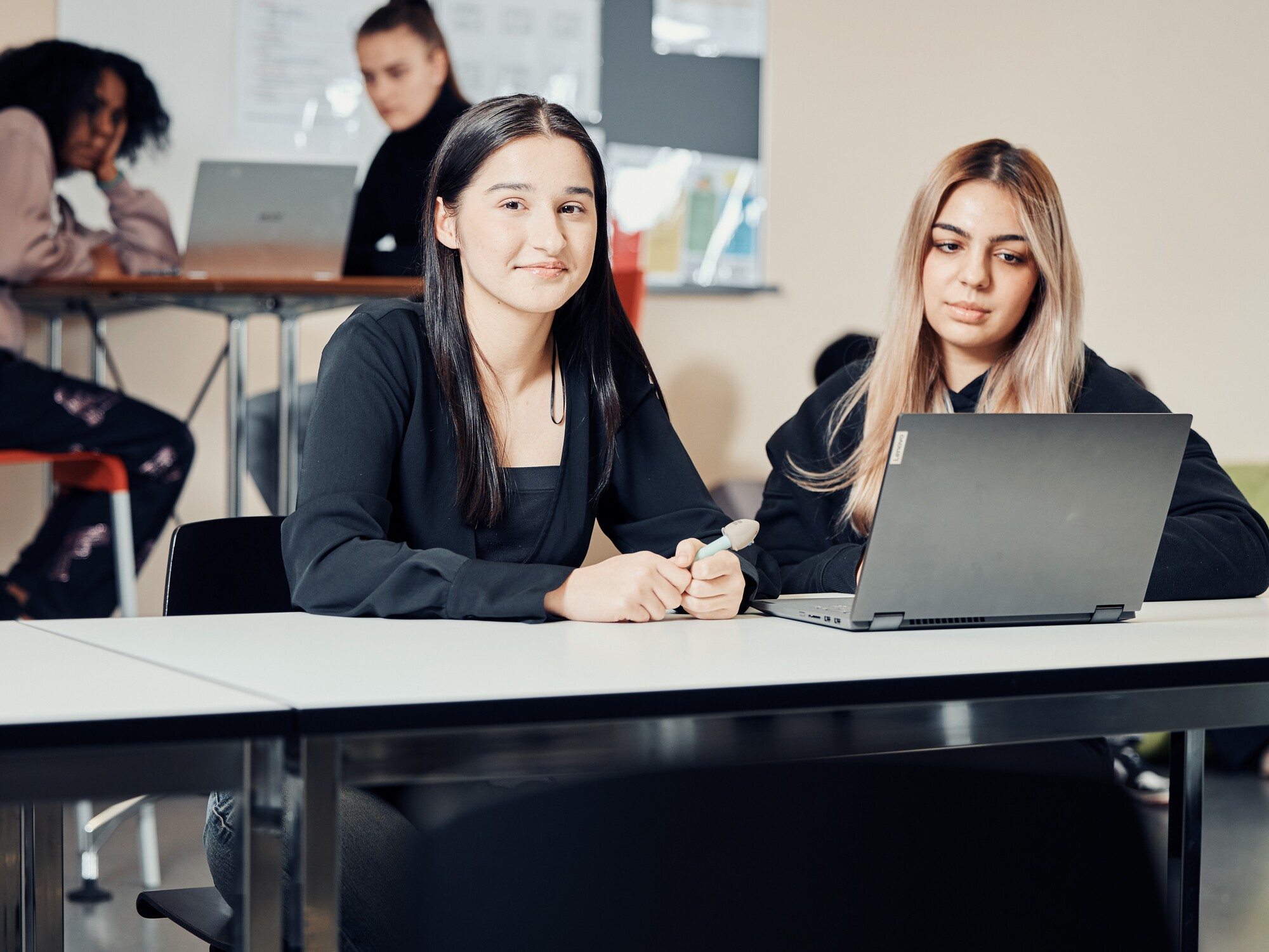 Schülerinnen an der KV Luzern Zwei Frauen sitzen an einem Tisch und arbeiten gemeinsam an einem Laptop.
