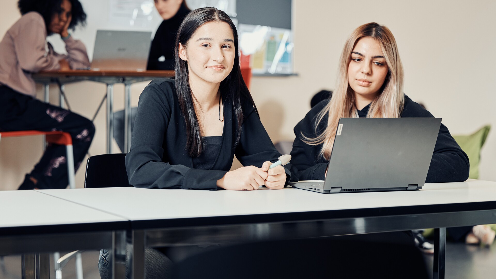 Schülerinnen an der KV Luzern Zwei Frauen sitzen an einem Tisch und arbeiten gemeinsam an einem Laptop.